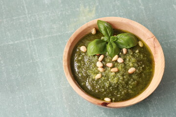 Fresh homemade pesto sauce with nuts and basilikum leaves parmeggiano cheese  on green table in the sunlight vegan food natural nutrition wooden bowl