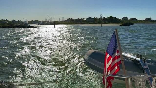 Rear view, sailboat leaving inlet for open water ocean sailing, blue sky and sunny
