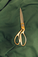 Steel tailor scissors on green natural fabric. Content for sewing workshops, ateliers for tailoring clothes