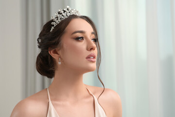 Beautiful young woman wearing luxurious tiara indoors, space for text © New Africa