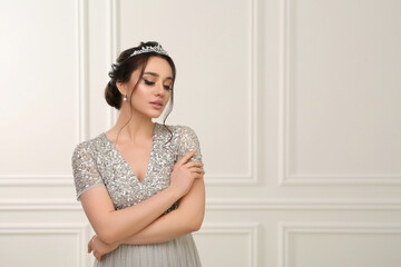 Beautiful young woman wearing luxurious tiara indoors, space for text