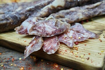 Dried or smoked sausage on a wooden table surrounded by spices and products. Meat production.