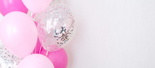 A bundle of pink and transparent air balloons with silver confetti, copy space for your text, tender pastel colors for a girlish party