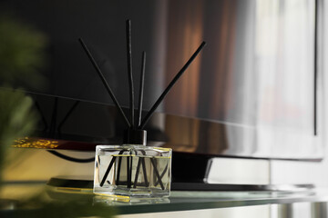 Aromatic reed air freshener on tv table indoors, space for text