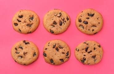 Many delicious chocolate chip cookies on pink background, flat lay