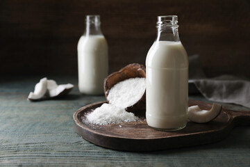 Delicious coconut milk, flakes and nut pieces on wooden table, space for text