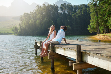 Young couple, lake and jetty with laughing, happiness and bonding with love in nature for holiday....