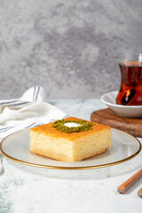 Revani dessert. Sweet semolina cake with pistachio. Ramadan sweets. Traditional Turkish cuisine delicacies. Revani dessert with syrup on a gray background.