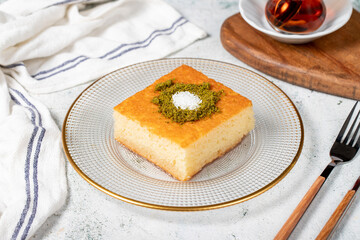 Revani dessert. Sweet semolina cake with pistachio. Ramadan sweets. Traditional Turkish cuisine delicacies. Revani dessert with syrup on a gray background.