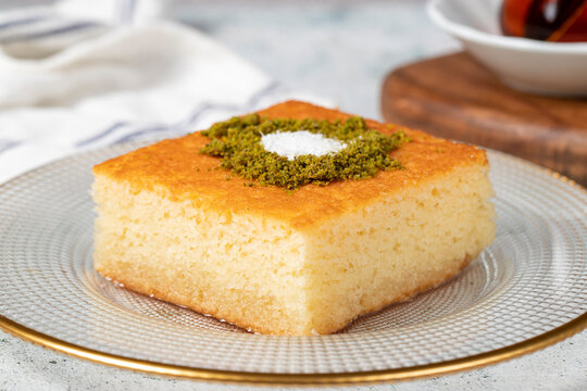 Revani dessert. Sweet semolina cake with pistachio. Ramadan sweets. Traditional Turkish cuisine delicacies. Revani dessert with syrup on a gray background. Close up