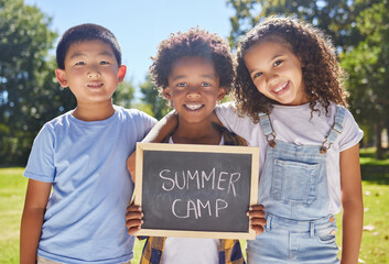 Summer camp, portrait or children with board in park together for fun, bonding or playing in outdoors. Sign, diversity or happy young best friends smiling or embracing on school holidays outside
