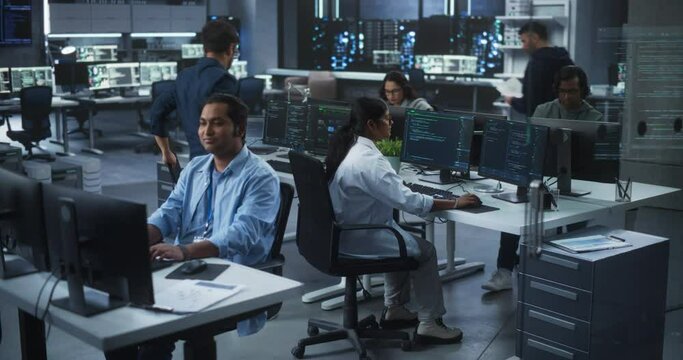 Team of Talented Young Indian Professionals Working in a Technological Research and Development Agency. Computer Screens with Software Code and Technical Neural Network Diagrams. High Angle Footage