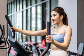 Fototapeta na wymiar Young asian girl jogging on a treadmill in a gym, Muscular athletes actively training in the gym, Female training at fitness center. Woman exercising cardio workout, exercise lose weight, listen music