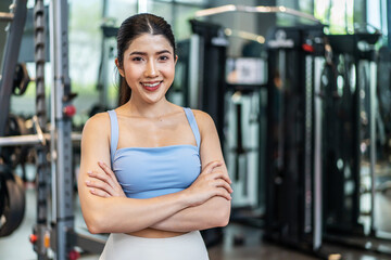 Fototapeta na wymiar Portrait of Active athlete asian woman in sportswear standing and crossing arms in gym. Sport people using machines exercise for health care then look at camera at fitness club