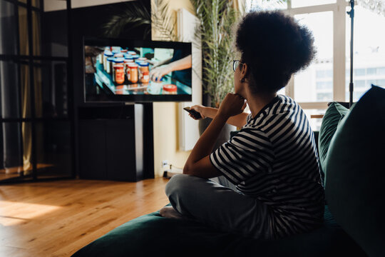 Back View Of Afro Woman Watching Tv While Sitting On Couch