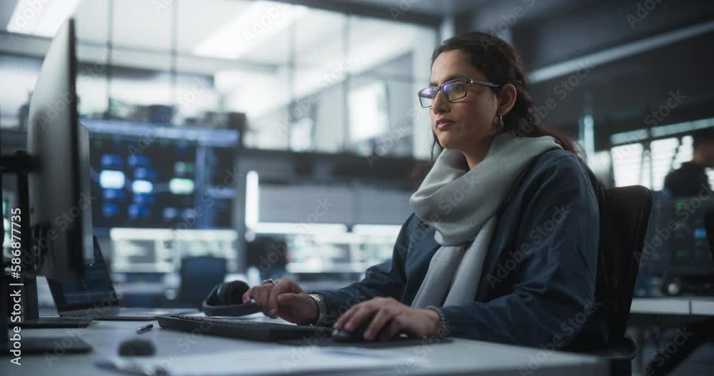 Poster Portrait of a Thoughtful South Asian Engineer Working on Computer in a Technological Corporate Office. Young Woman Writing Software Code for an Innovative Internet and Software as a Service Project