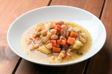 Minestra di verdure e legumi - zuppa di zucchine, patate, carote, bietole, sedano, fagiolini, ceci e fagioli - cibo vegetariano 