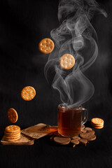 Obraz na płótnie Canvas hot tea with cookies on a black background, a cup of hot tea