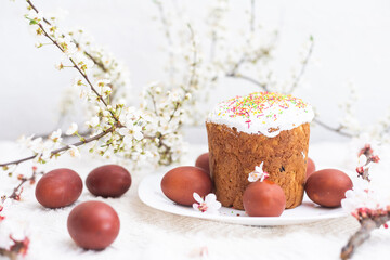 Easter composition. A blooming apricot branch, painted eggs and a glazed Easter cake decorated with sugar sprinkles