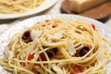 Delicious pasta with anchovies, tomatoes and parmesan cheese on table, closeup