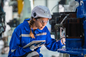 woman engineer in uniform helmet inspection check control heavy machine robot arm construction installation in industrial factory. technician worker check for repair maintenance electronic operation