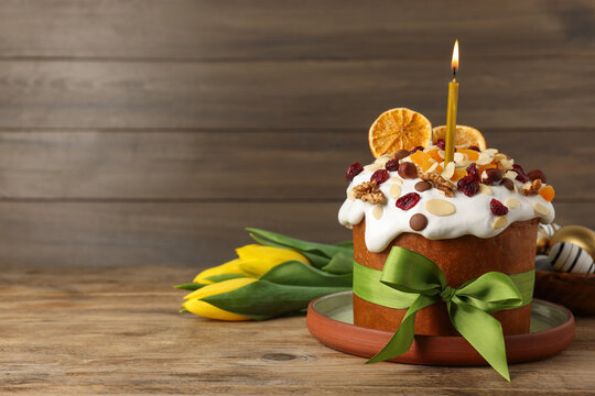 Tasty Easter cake with dried fruits, flowers and decorated eggs on wooden table. Space for text