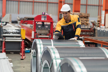 Metalwork manufacturing, warehouse of raw materials. Male factory worker inspecting quality rolls of metal sheet in factory during manufacturing process, wearing safety uniform, use digital tablet