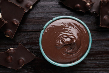 Bowl with tasty paste and pieces of chocolate on wooden table, flat lay