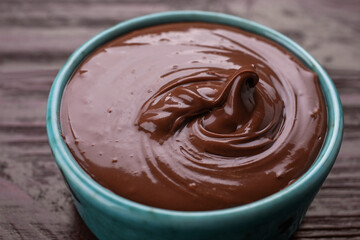 Bowl with tasty chocolate paste on wooden table, closeup