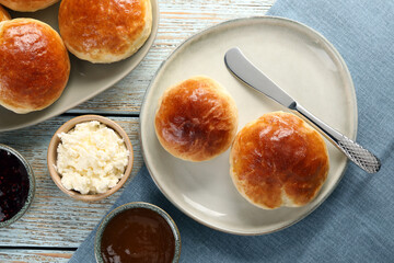 Tasty scones prepared on soda water, chocolate paste, jam and cottage cheese on wooden table, flat lay