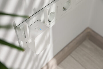 Wireless Wi-Fi repeater on white wall indoors, above view