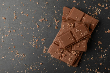 Pieces of tasty chocolate on grey table, top view. Space for text