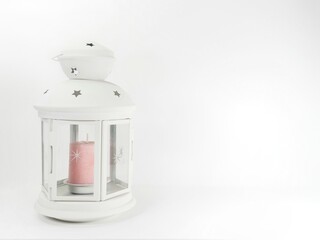 candil blanco con una vela rosa sobre un fondo blanco con espacio para escribir texto