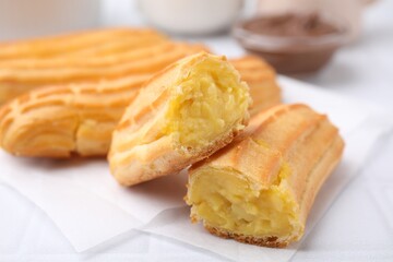 Delicious eclairs on white table, closeup view