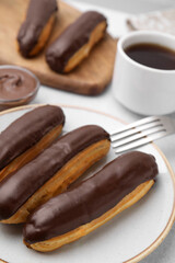 Delicious eclairs covered with chocolate on grey table, closeup