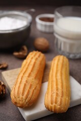 Delicious eclairs, walnuts and milk on grey table, closeup