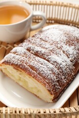 Delicious yeast dough cake and tea on wicker tray, closeup
