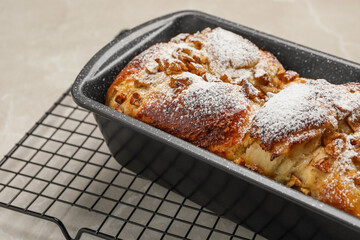 Delicious yeast dough cake in baking pan on beige table, closeup