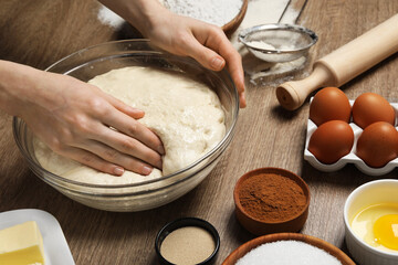 Fototapeta premium Woman kneading yeast dough for cake at wooden table, closeup