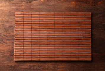 Bamboo mat on wooden table, top view. Space for text