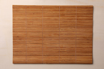 Bamboo mat on beige table, top view. Space for text