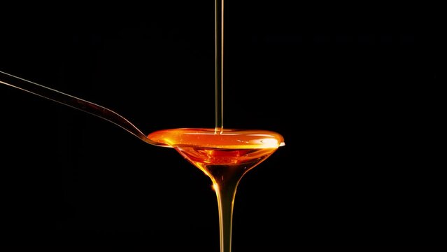 honey dripping from a spoon and black background