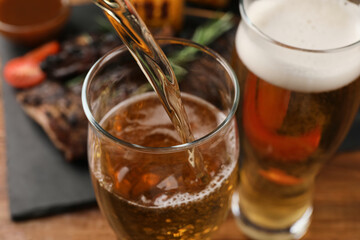 Pouring beer into glass at table, closeup