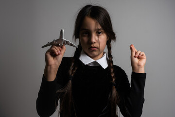 A girl with braids in a gothic style on a dark background with toy airplane
