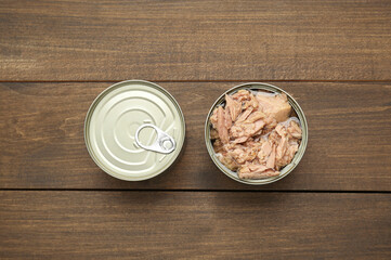 Obraz na płótnie Canvas Tin cans with canned tuna on wooden table, flat lay