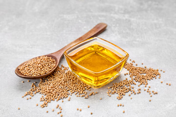 Bowl of natural oil and mustard seeds on light grey table