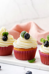 Cupcakes, muffins decorated with cream, berries and green mint leaves. Delicious homemade dessert. Pastry.