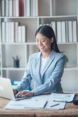 Asian businesswoman talking on phone, using laptop, looking at screen, entrepreneur manager consulting client by call, looking at computer screen, discussing