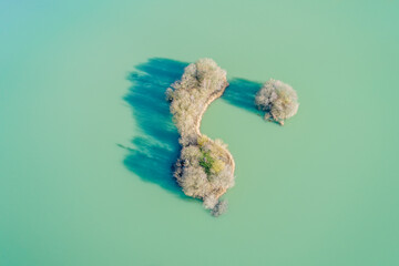 aerial drone view of a small island in a green water lagoon