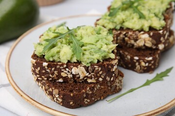 Delicious sandwiches with guacamole and arugula on plate, closeup